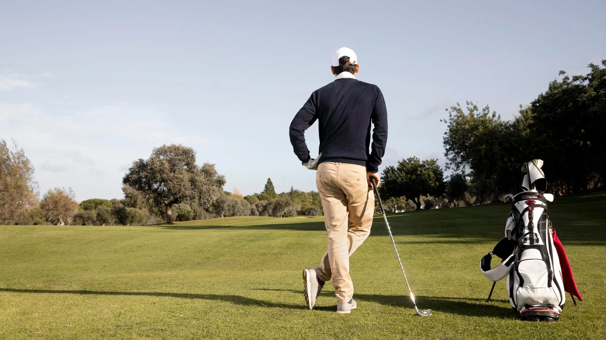 Golfeur appuyé sur son fer, son sac trépied posé sur le fairway