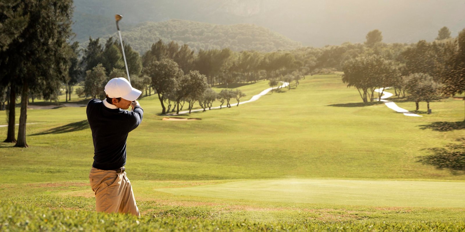 Golfeur en plein swing sur un parcours vallonné