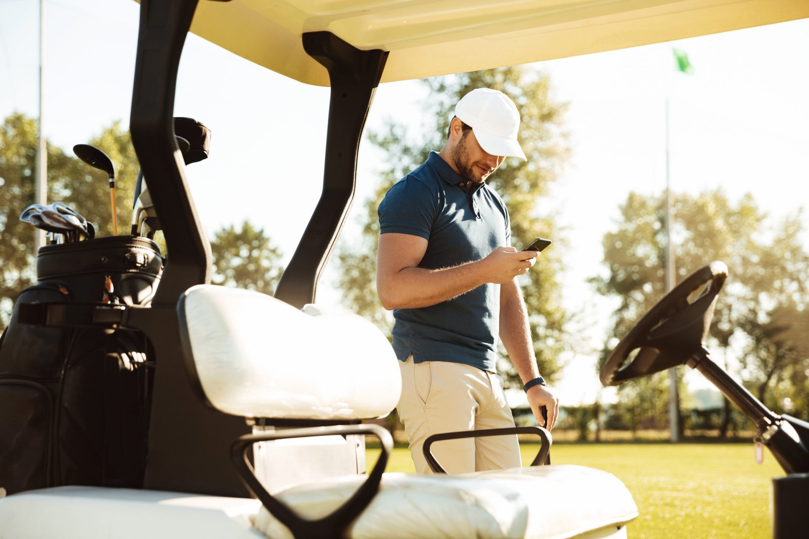 Golfeur consultant son téléphone à côté d’une voiturette